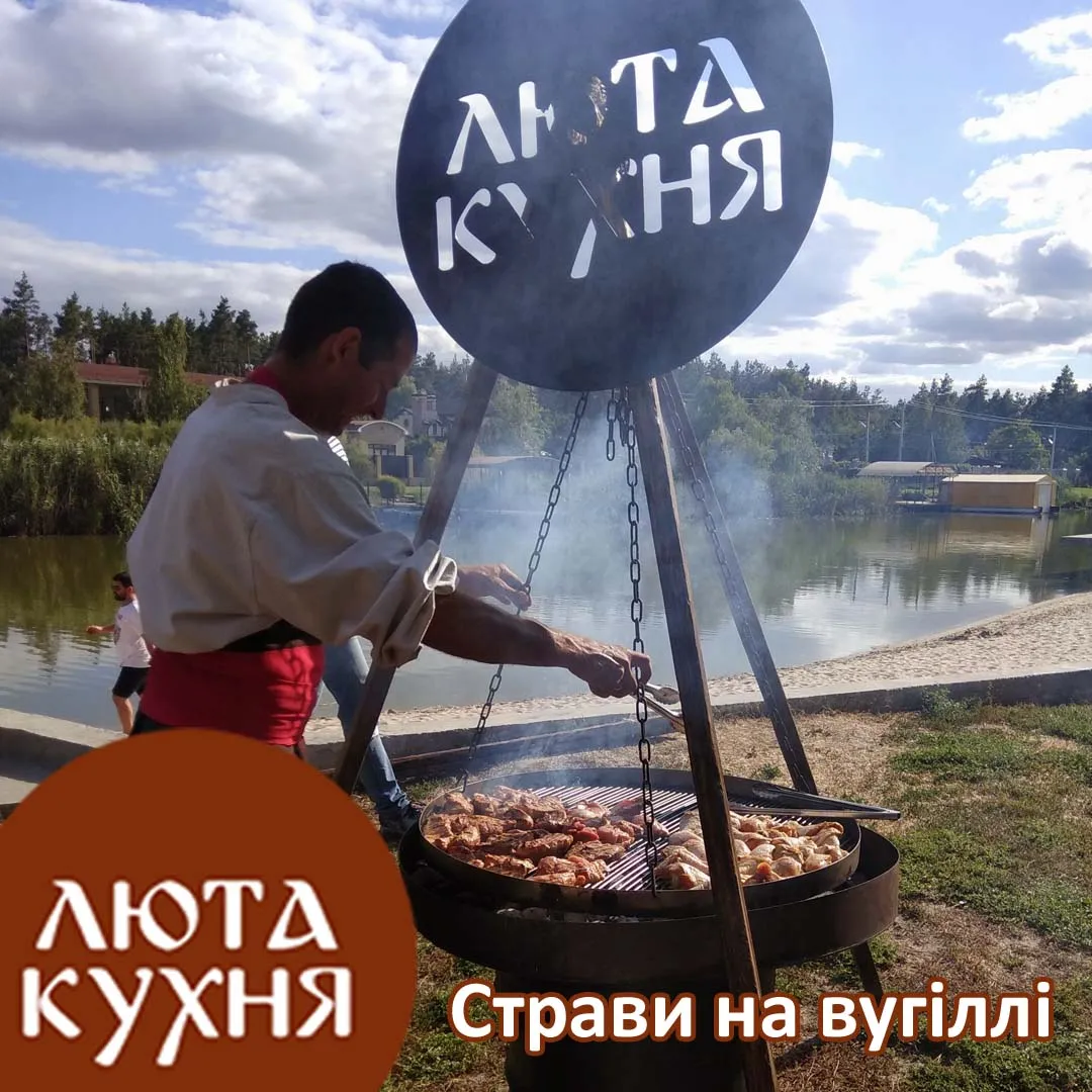 Козак готує м'ясо на великому грилі над вугіллям